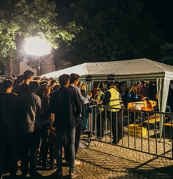 Einlasskontrolle durch OZ Security am Abend vor einem Zelt mit Ticketverkauf